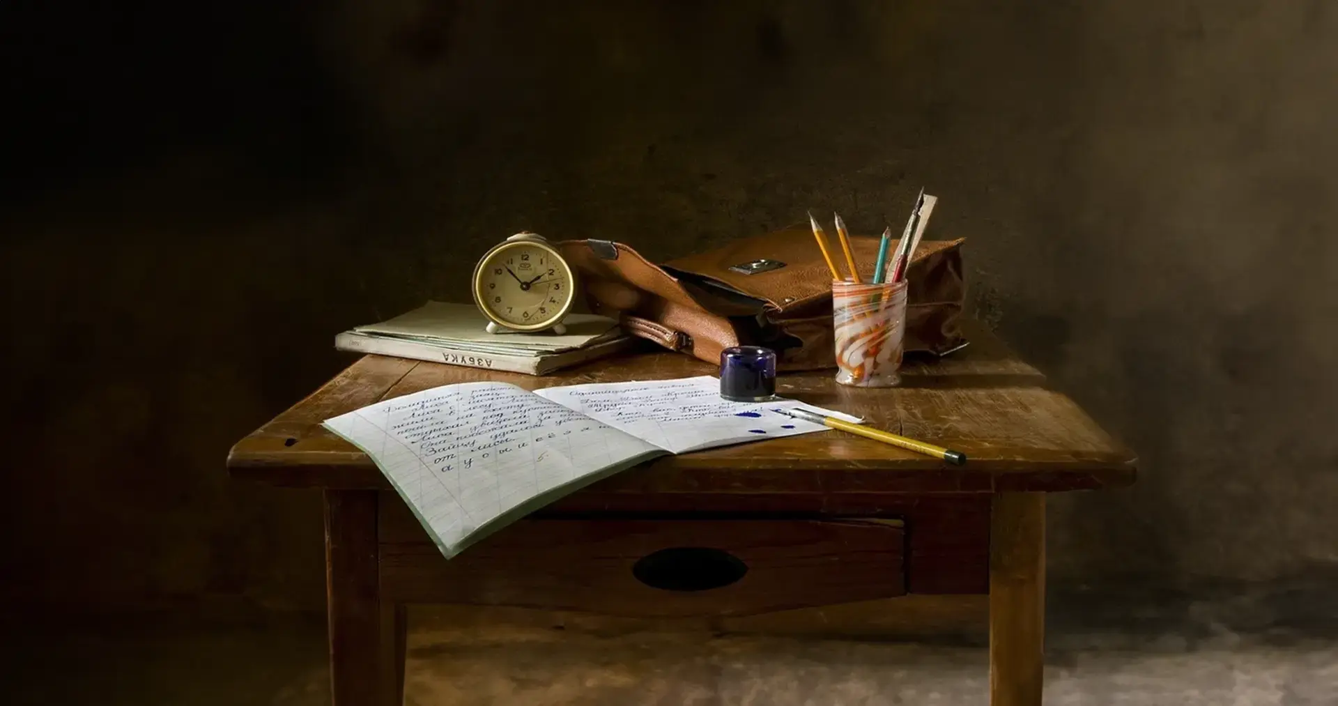 Mesa con cuaderno, lápices y reloj