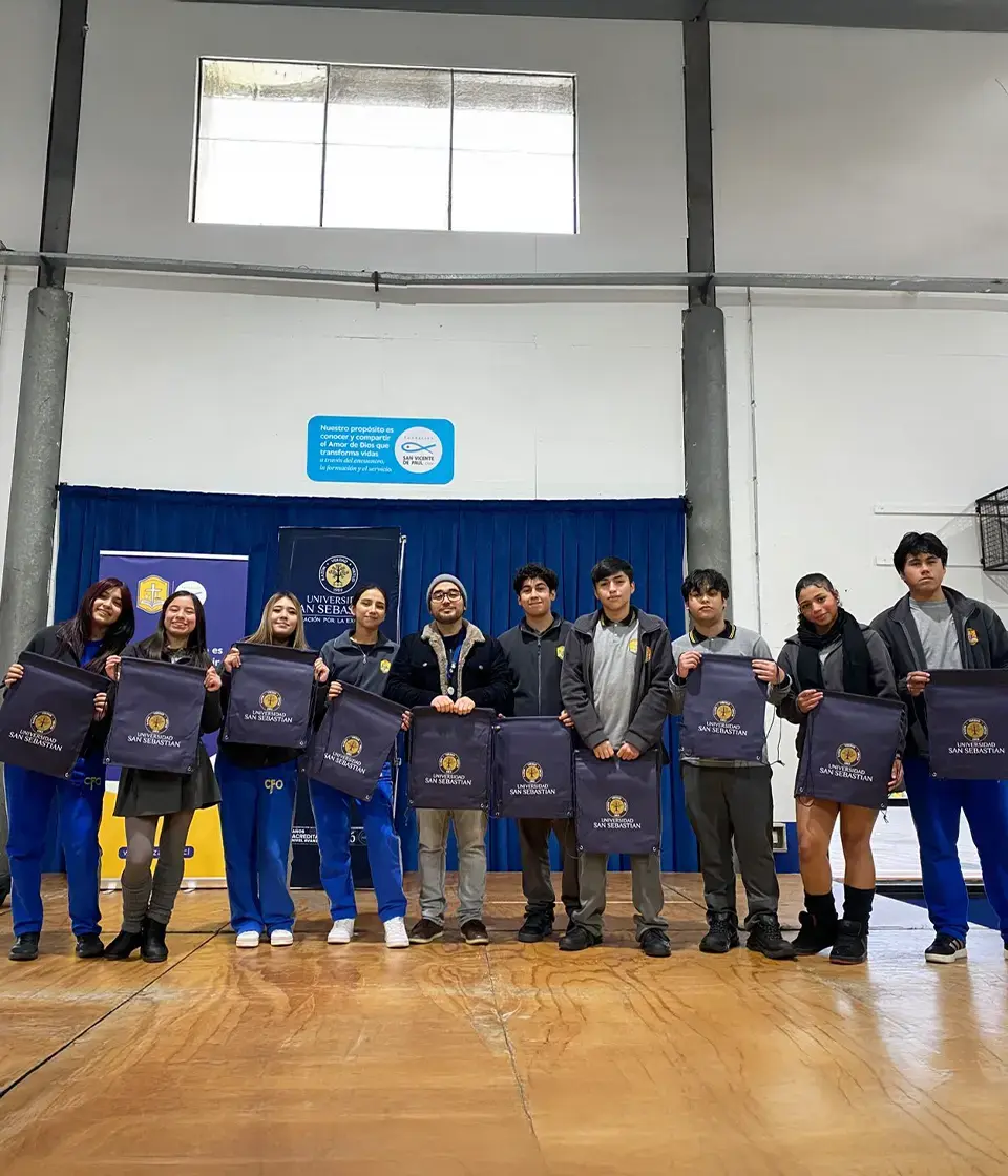 Grupo de alumnos posando en un gimnasio con bolsas institucionales de regalo. Grupo de alumnos posando en un gimnasio con bolsas institucionales de regalo.